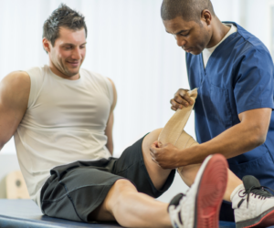 man getting knee taped up